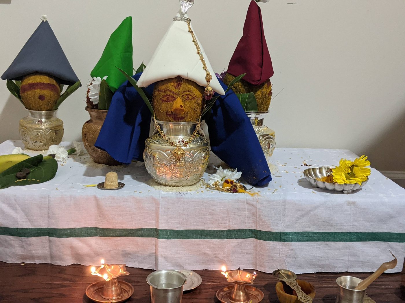 Varalakshmi kalasha decorated as the Goddess, with lamps and offerings